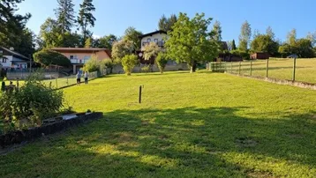 Weitläufige Rasenfläche mit Blick auf die umliegende Hügellandschaft und weitere Häuser.