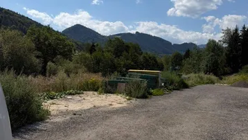 Weitläufiges Grundstück mit Blick auf die grüne Berglandschaft unter blauem Himmel.