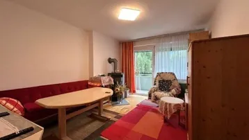 Wohnzimmer mit Holzofen, Essbereich und Zugang zum Balkon.