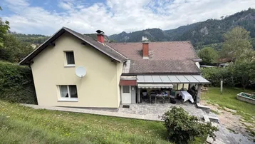 Ansicht des Hauses von oben mit überdachter Terrasse und Blick auf die umliegende Berglandschaft.
