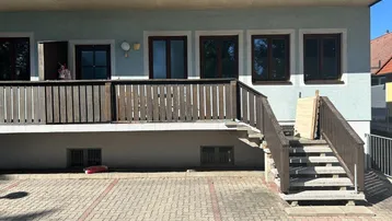 Fassade eines Wohngebäudes mit Balkonstruktur und Außentreppe an einem sonnigen Tag.