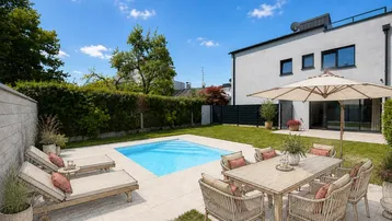 Sonniger Gartenbereich mit privatem Pool, Liegestühlen und Essbereich im Freien.