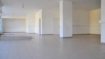 Geräumiger, leerer Gewerberaum mit hellen Fliesenböden und weißen Wänden, bereit für die individuelle Gestaltung.