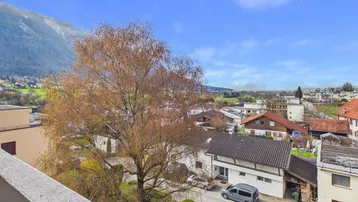 Weitblick vom Balkon über die umliegende Wohngegend und die majestätischen Berge im Hintergrund.