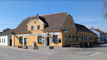 Traditionelles Gasthaus "Zum Einhorn" mit gelber Fassade und braunem Dach an einer Straßenecke.