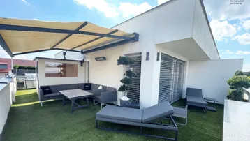 Geräumige Dachterrasse mit gemütlicher Lounge-Ecke, Kunstrasen und ausfahrbarer Markise für entspannte Stunden im Freien.