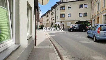 Blick auf die Straße und die umliegenden Gebäude in einer städtischen Umgebung mit geparkten Autos.