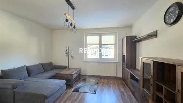 Geräumiges Wohnzimmer mit bequemer Couch, Holzboden und modernen Möbeln, ideal zum Entspannen.