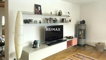 Modernes Wohnzimmer mit Holzboden, Kaminofen und stilvoller Einrichtung.