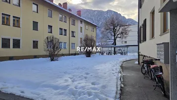 Mehrfamilienhaus in winterlicher Landschaft mit Schnee und Bergblick im Hintergrund.