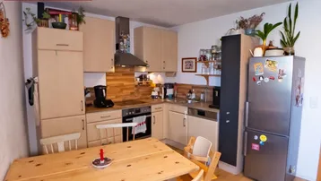 Gemütliche Küche mit hellen Holzfronten, Essbereich und modernen Geräten.