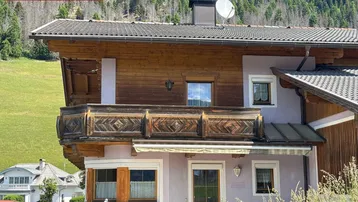 Chalet-Stil Hausfassade mit Holzbalkon und Bergblick in alpiner Umgebung.