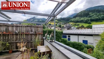 Geräumige Terrasse mit Holzboden, Bergblick und dekorativen Gartenzwergen.