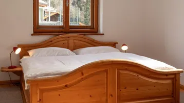 Traditionelles Schlafzimmer mit großem Holzbett, Holzboden und Fenster mit Bergblick.