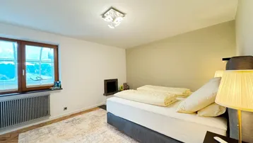 Schlafzimmer mit Doppelbett, Teppich und einem integrierten Kaminofen.