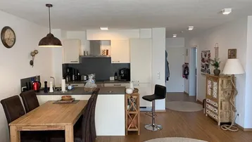 Moderne offene Küche mit Essbereich, Laminatboden und integrierten Geräten in hellem Design.
