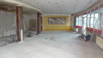 Großzügiger Innenraum im Rohbauzustand mit Säulen und großen Fenstern, bereit für den Ausbau.