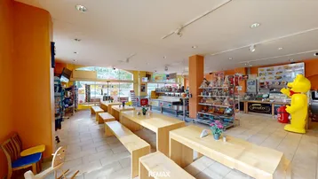 Geräumiger Innenbereich eines Geschäfts oder Restaurants mit Holztischen, Bänken und großen Fenstern.