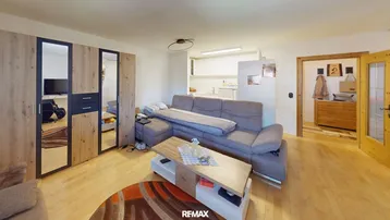 Gemütliches Wohnzimmer mit hellem Holzboden, bequemer Couch und integriertem Stauraum.