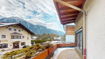 Große Terrasse mit Blick auf die schneebedeckten Berge und umliegende Häuser.