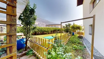 Gepflegter Gartenbereich mit Holzzaun, Grünflächen und einem kleinen Schuppen.