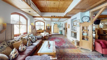 Gemütliches Wohnzimmer im alpinen Stil mit Holzbalkendecke, Kamin und traditionellen Teppichen.