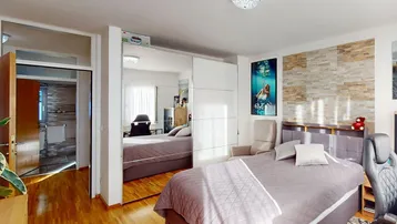 Schlafzimmer mit Bett, Spiegelschrank und Schreibtisch, mit direktem Zugang zum Badezimmer.