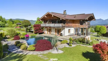 Großzügiges Anwesen mit traditionellem Holzhaus, weitläufigem Garten und privatem Swimmingpool in alpiner Umgebung.