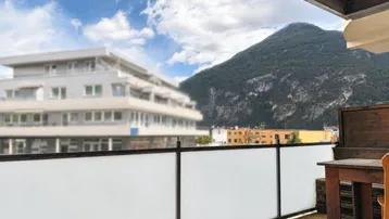 Weitblick vom Balkon auf die umliegende Berglandschaft und Gebäude.