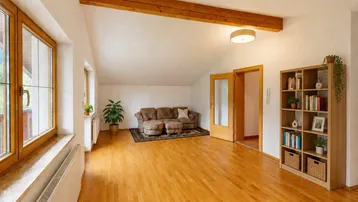 Helles Wohnzimmer mit Holzbalken, Parkettboden und großen Fenstern mit Bergblick.