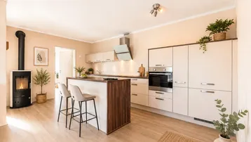 Moderne offene Küche mit Kochinsel, integrierten Geräten und gemütlichem Holzofen.
