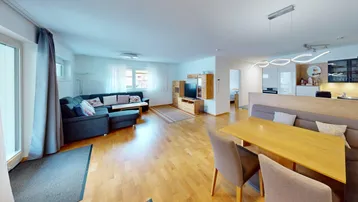 Geräumiger Wohn-Essbereich mit Holzboden, gemütlicher Sitzecke und Zugang zum Balkon.