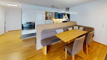 Moderne Küche mit integriertem Essbereich und Holzboden, ideal für gesellige Mahlzeiten.