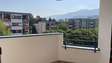 Geräumiger Balkon mit Blick auf die umliegenden Gebäude und die beeindruckende Berglandschaft.