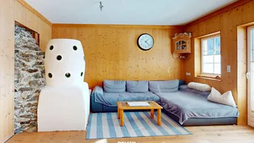 Gemütliches Wohnzimmer im alpinen Stil mit Holzwänden, Kachelofen und bequemer Sitzecke.