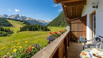 Geräumiger Balkon mit bunten Blumenkästen und atemberaubendem Bergblick.