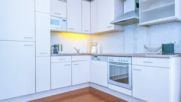 Funktionale Küche mit weißen Schränken, integrierten Geräten und Holzboden.