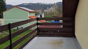 Balkon mit Holzzaun und Blick auf die umliegende grüne Landschaft und Berge.