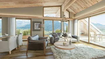 Helles Wohnzimmer mit Holzbalkendecke, großen Fenstern und Bergblick, ideal zum Entspannen.