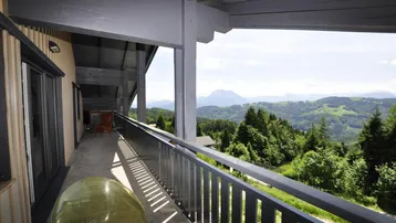 Geräumiger Balkon mit Holzboden und weitem Blick auf die umliegende Berglandschaft.