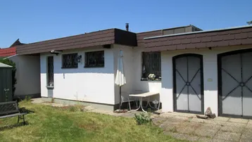 Seitenansicht des Hauses mit Rasenfläche und einem kleinen gepflasterten Bereich im Freien.