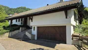 Hausfassade mit Garagentor, gepflasterter Auffahrt und Außentreppe zum Eingangsbereich.