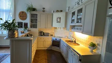 Traditionelle Küche mit Fischgrätparkett, Einbauküche und einem historischen Holzofen.