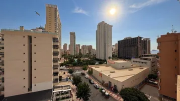 Panoramablick über die belebte Stadtstraße mit hohen Gebäuden unter strahlendem Sonnenschein.