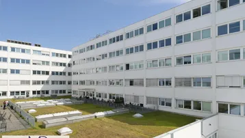 Innenhof eines modernen Bürogebäudes mit begrünten Flächen und vielen Fenstern.