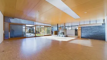 Geräumiger, offener Wohnbereich mit Holzboden, Kamin und großen Glasfronten zum Innenhof.