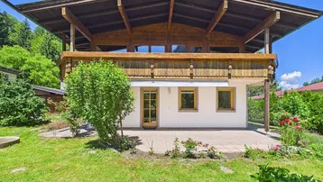 Traditionelles Haus mit Holzbalkonen, weißer Fassade und direktem Zugang zum grünen Garten.
