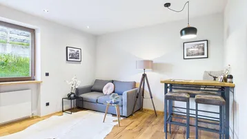 Helles Wohnzimmer mit Holzboden, gemütlichem Sofa und einer modernen Bartheke.