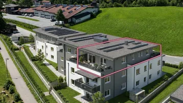 Moderne Wohnanlage mit mehreren Einheiten und Solarpaneelen auf dem Dach, umgeben von grüner Landschaft.
