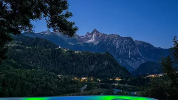 Beleuchteter Whirlpool bei Nacht mit malerischem Blick auf die beleuchteten Berge.